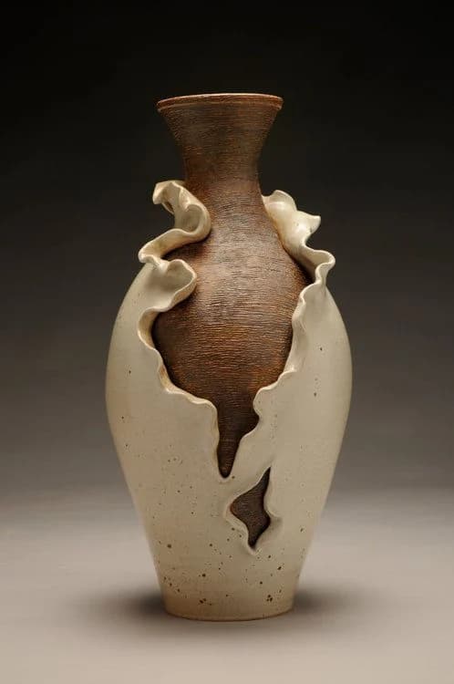 A tall ruffled stoneware vase on a dark ground
