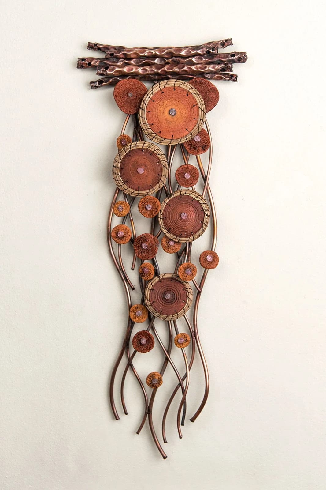 A hanging assemblage of copper discs on twisted wood