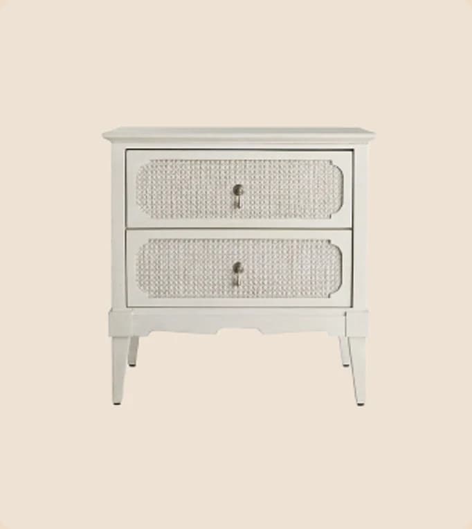 A white nightstand with cane drawer fronts
