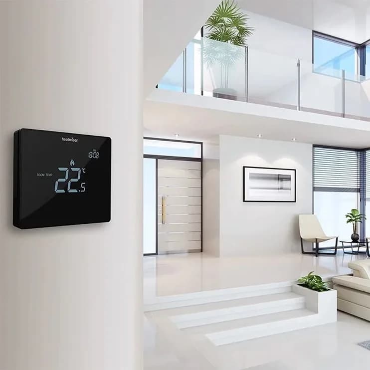 A wall thermostat in a bright double-height hall