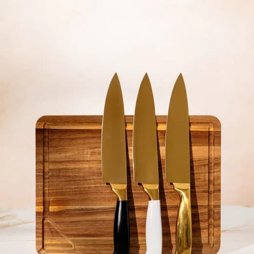 Three brass-handled knives on a walnut board