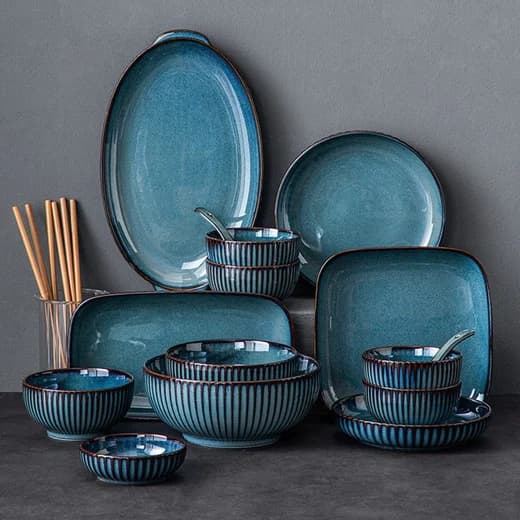 A stacked set of teal reactive-glaze plates and bowls