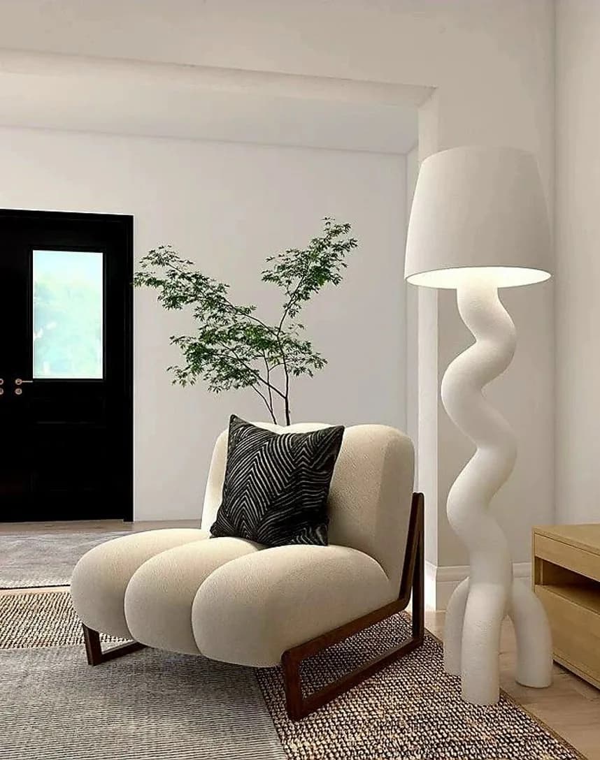 A boucle armchair beside a sculptural white floor lamp
