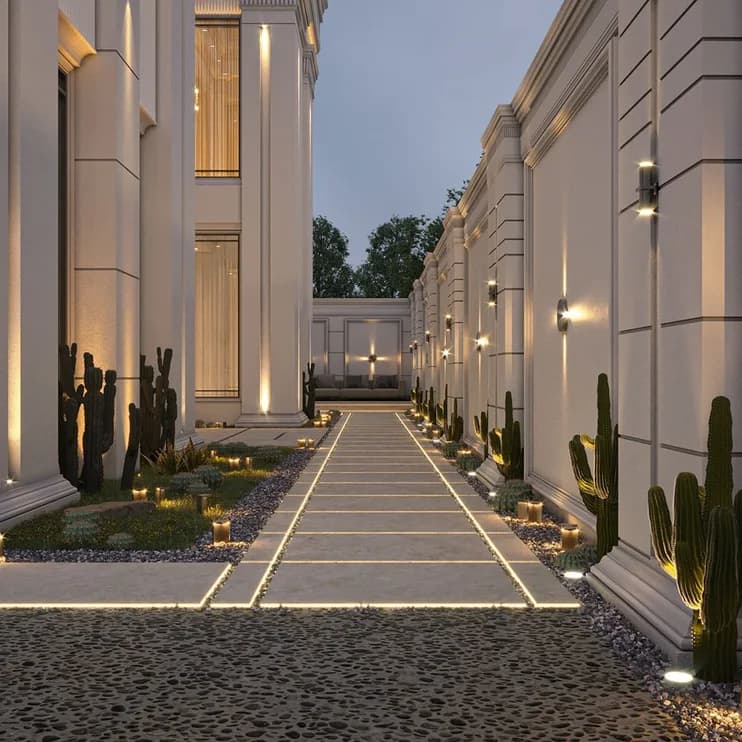 A lit walled driveway at dusk