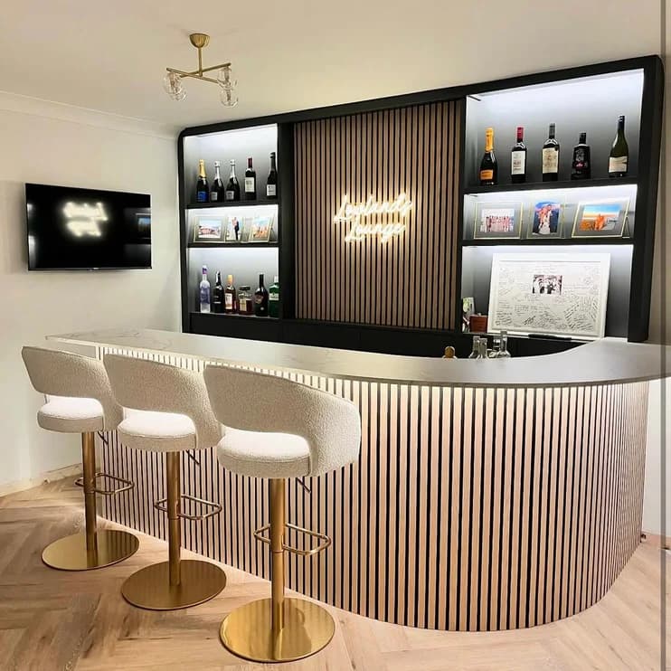 A curved home bar with a lit bottle display
