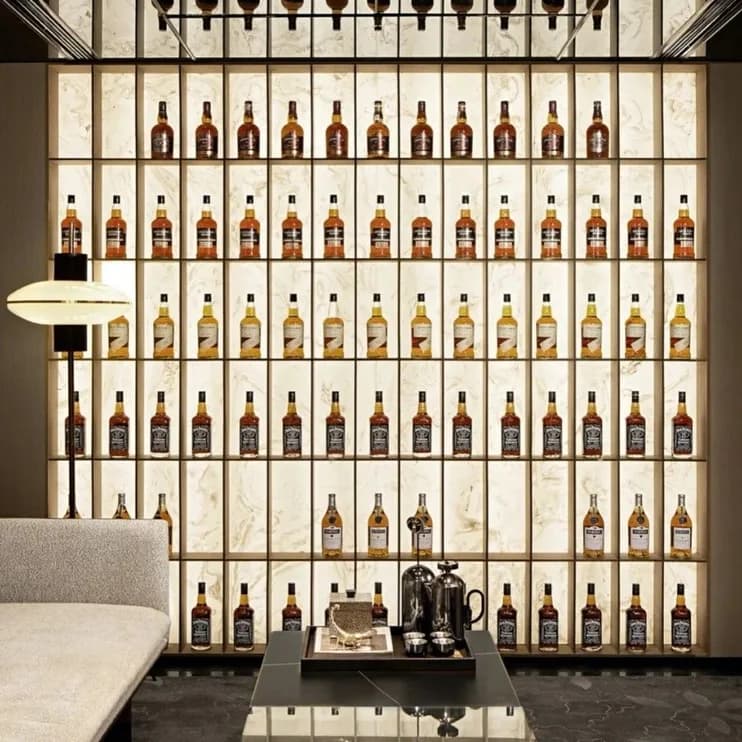 A wine wall of backlit bottles over a dark marble floor