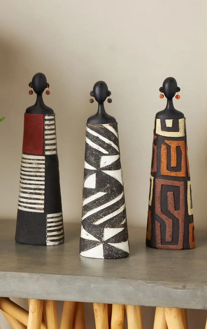 Carved painted figures standing on a concrete console