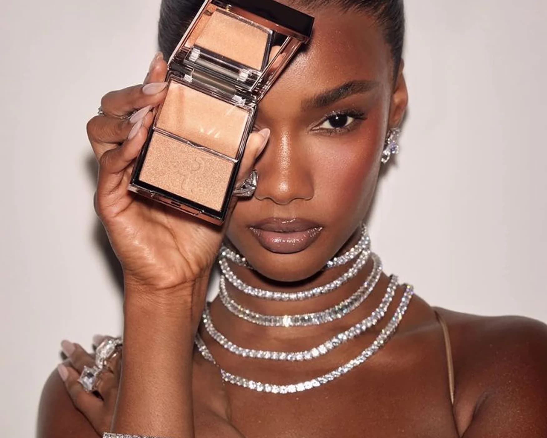A model holding a compact against a pale ground
