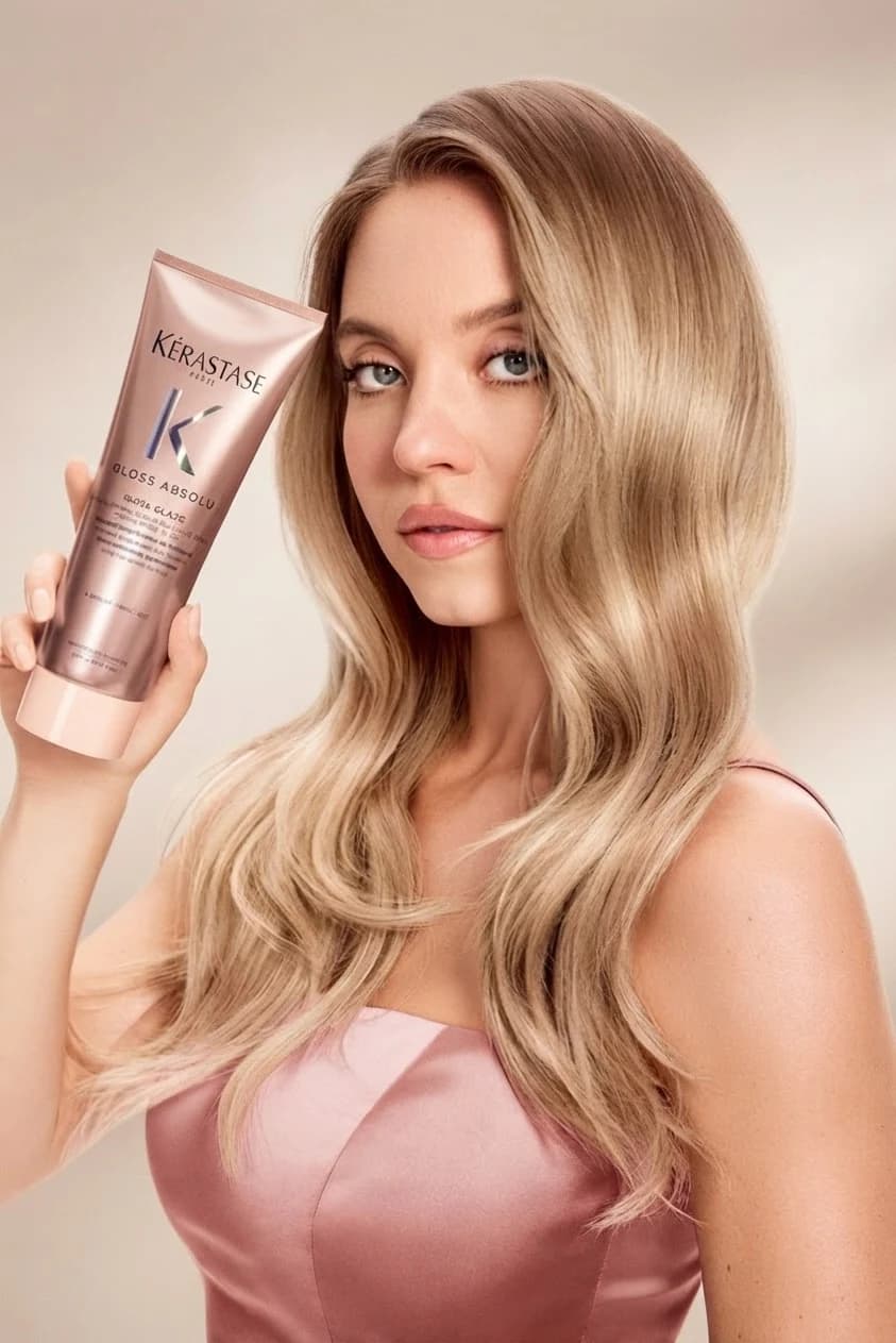 A model holding the tube beside long, glossy hair