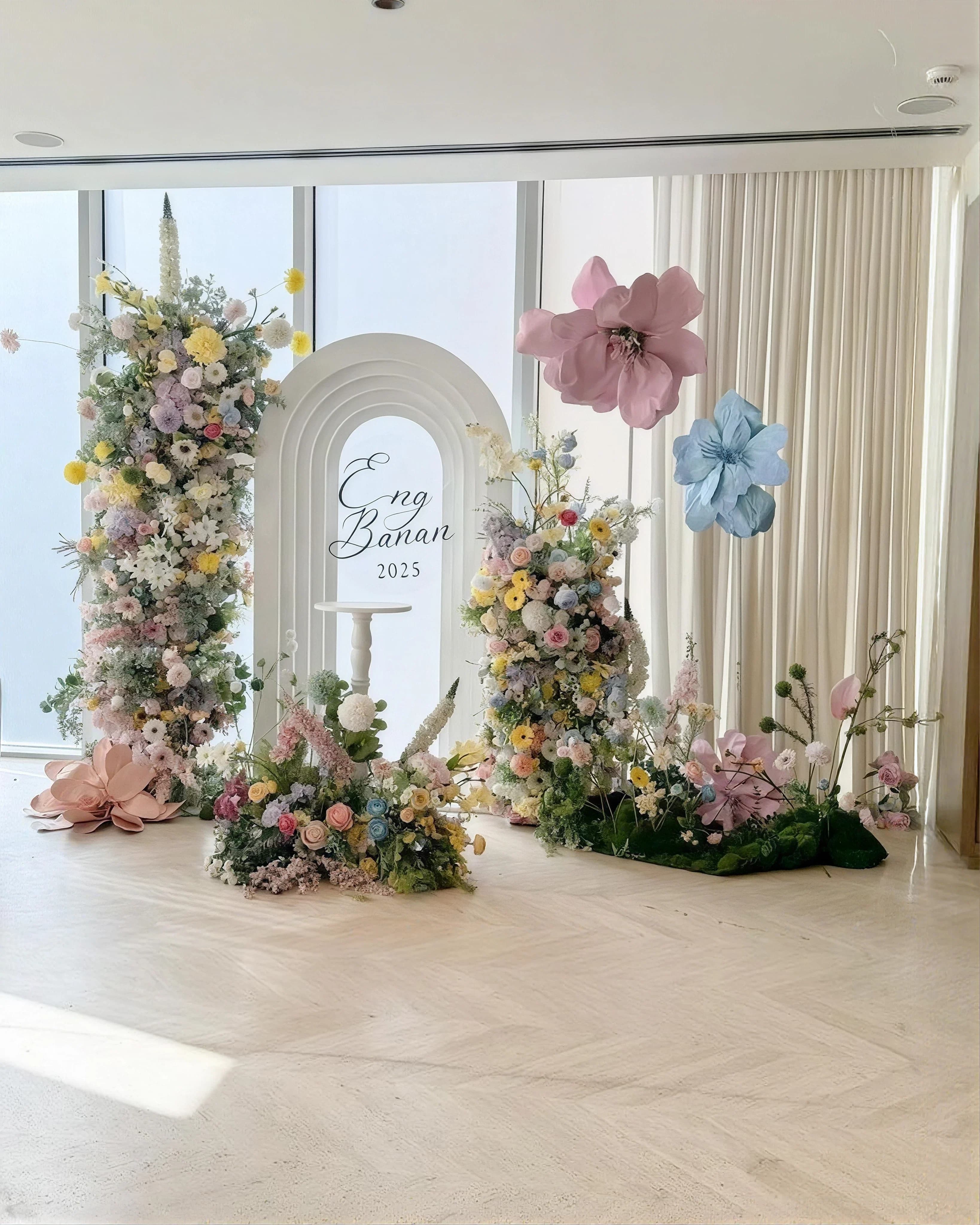 An engagement backdrop arch banked with pastel flowers