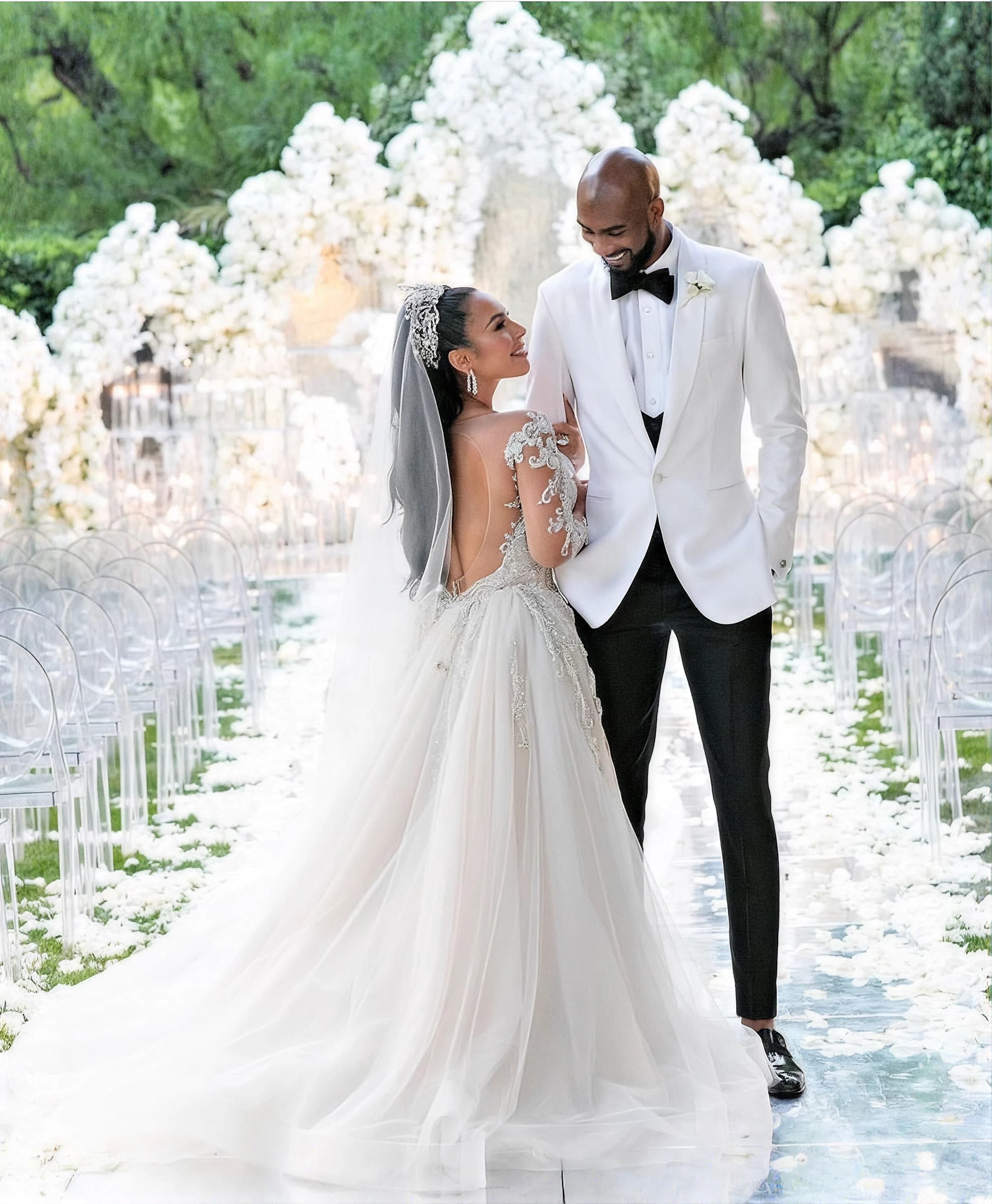 A bride and groom under an arch of white blossom