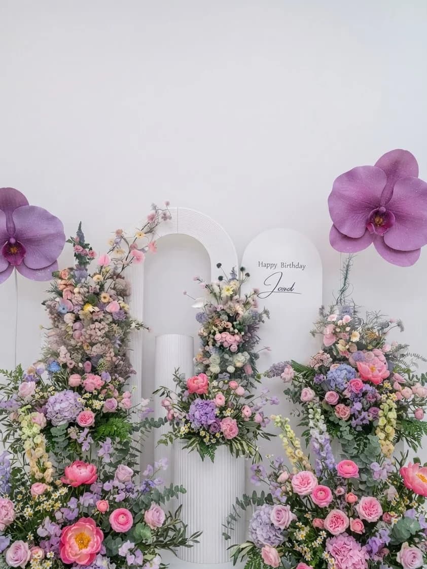 A birthday backdrop of pastel arches hung with orchids and mixed blooms