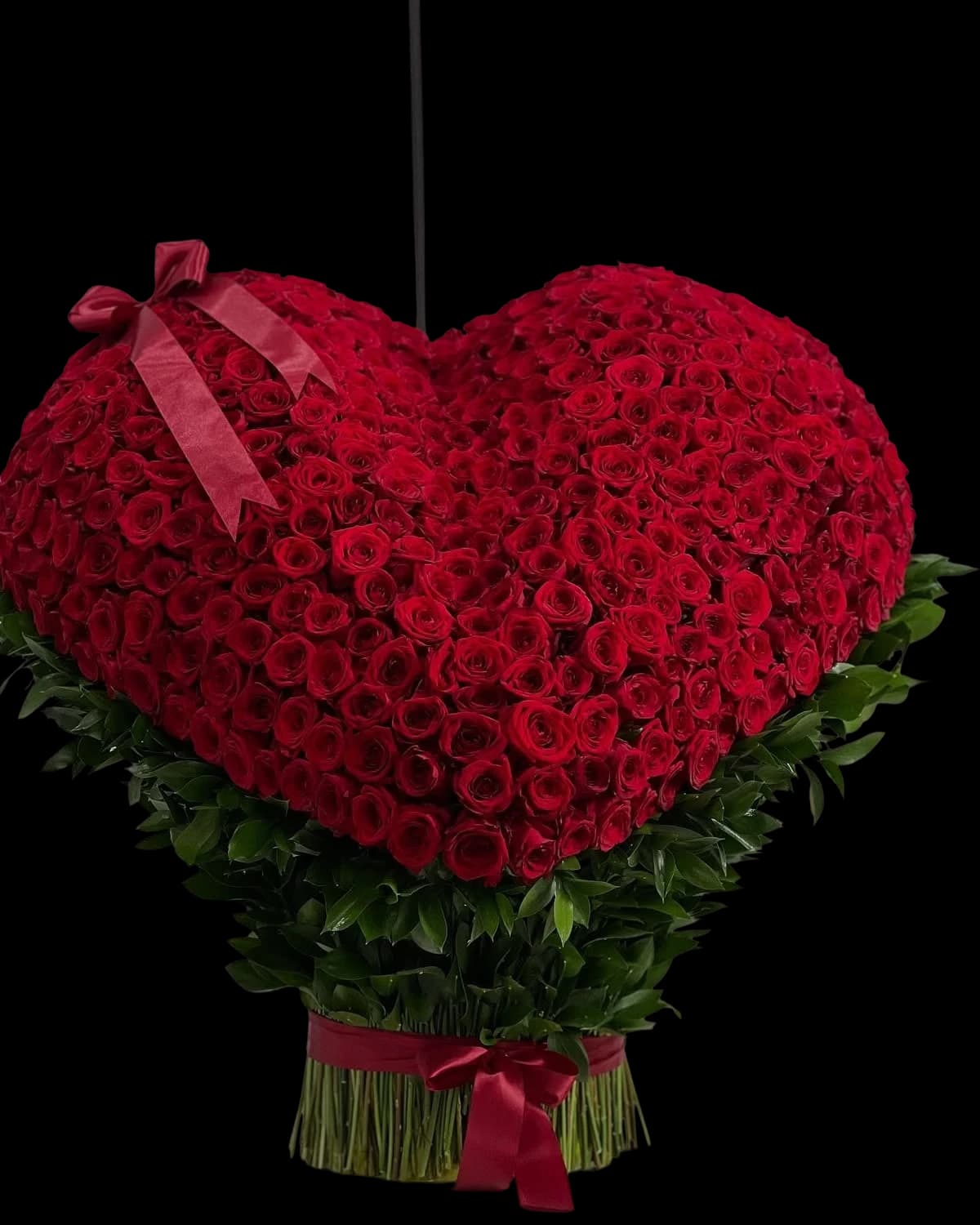 A hanging heart massed with red roses over a foliage collar