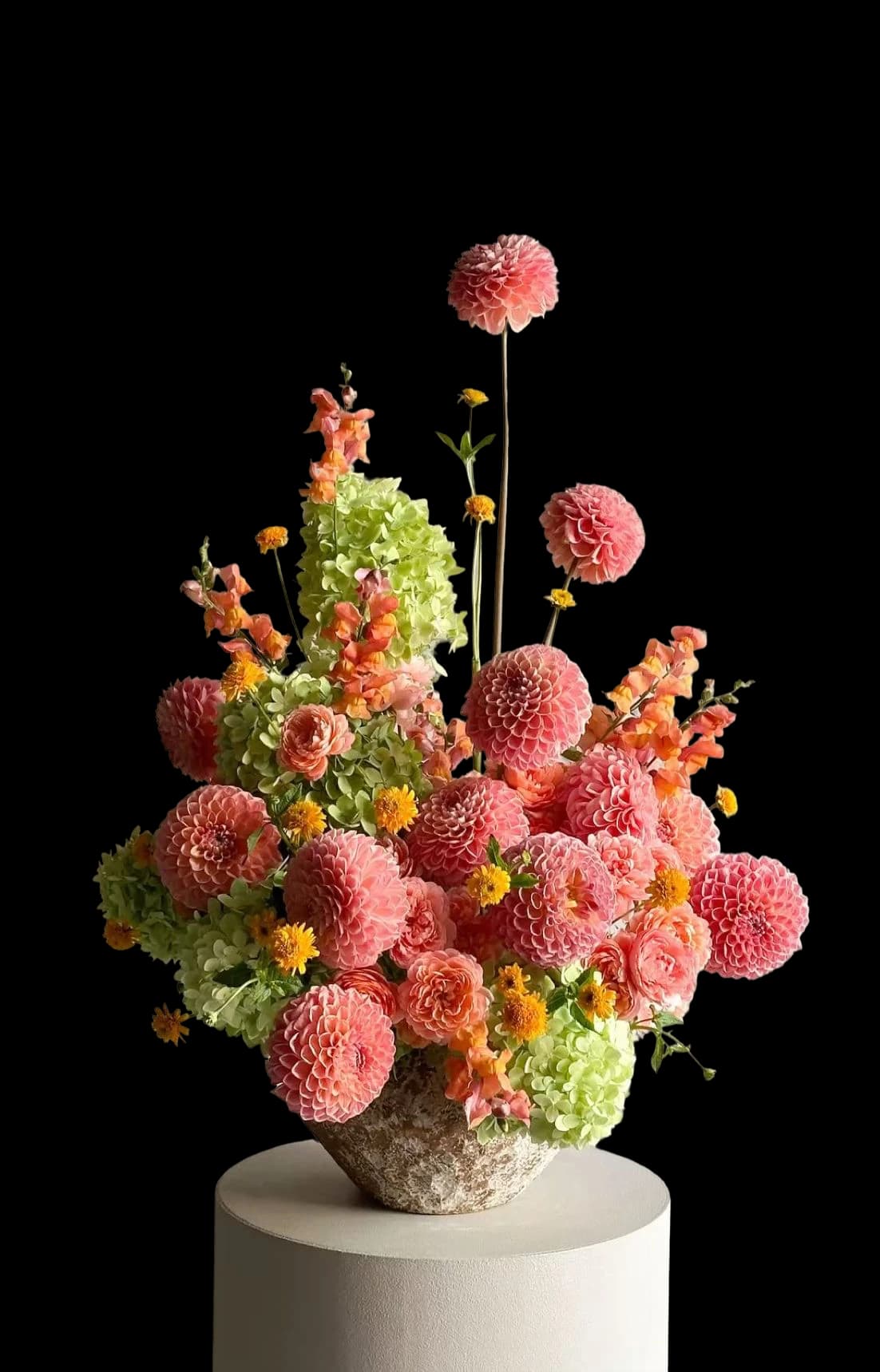 A tall footed arrangement of coral chrysanthemums and berries