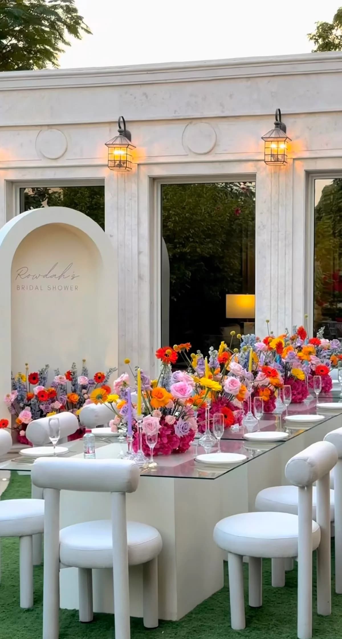 A bridal shower table lined with bright mixed arrangements