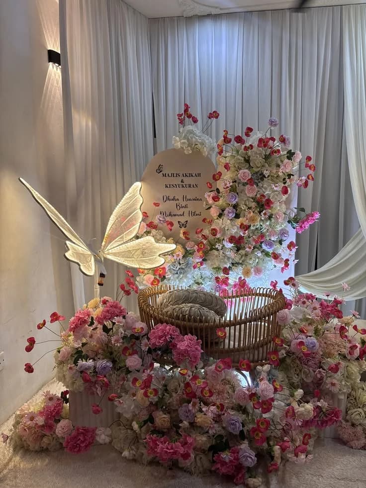 A christening display of banked pink blooms around a gilded butterfly