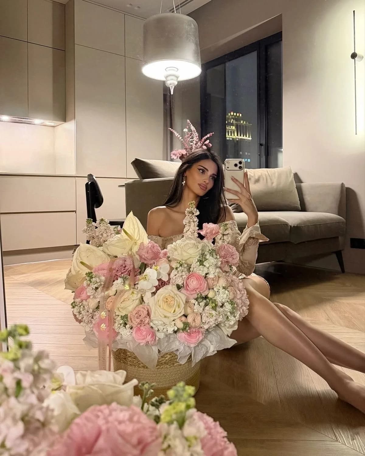 A woman on a sofa with an armful of blush roses and peonies