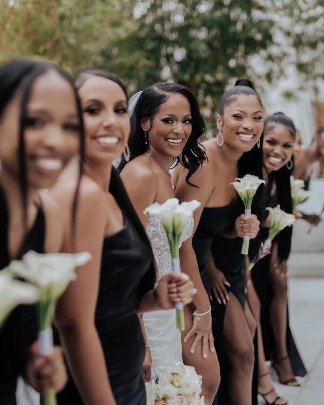 Bridesmaids in black holding white calla lily bouquets