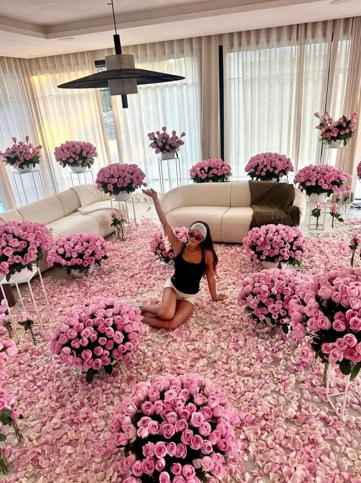 A room floored with pink roses, a woman seated among them