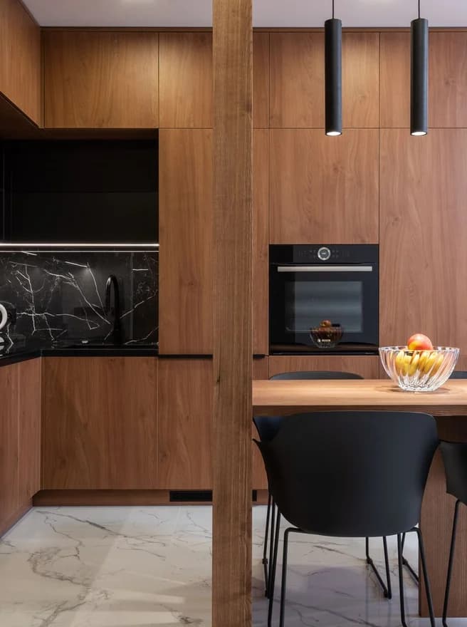 A walnut kitchen with a built-in oven and pendant lights