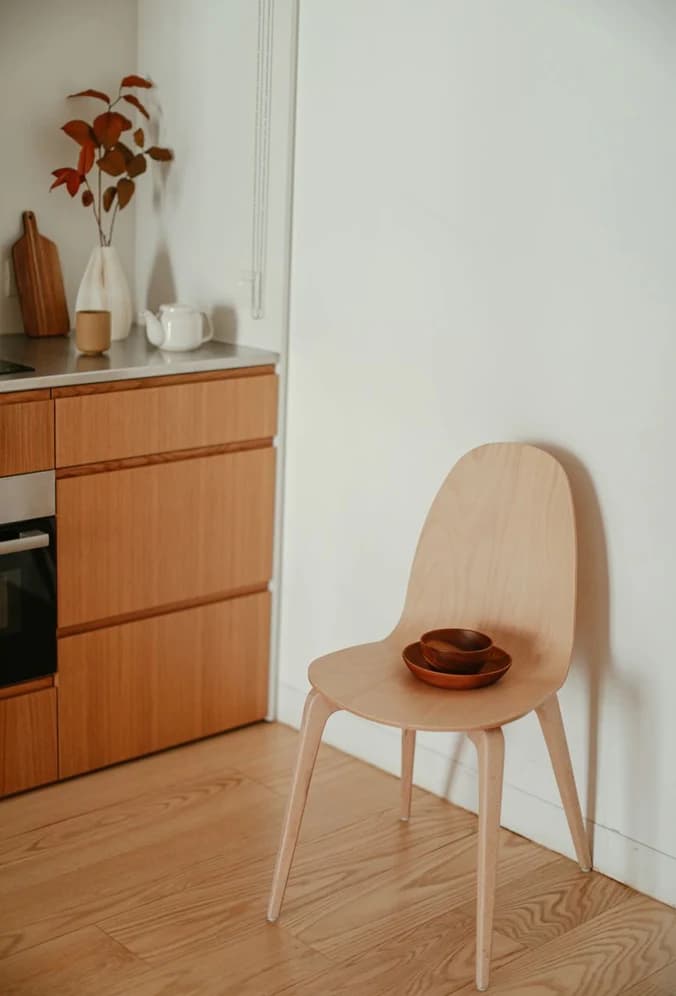A daylit corner with a timber kitchen and a pale moulded chair