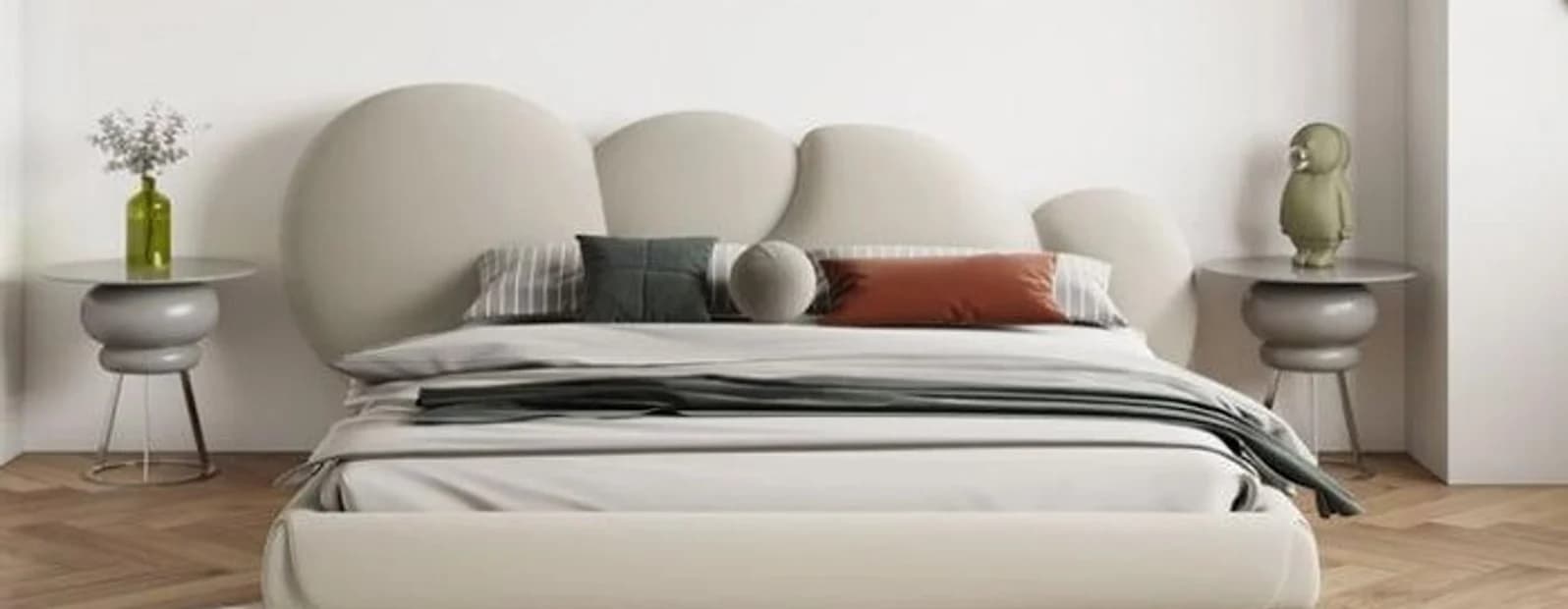 A bed with a rounded padded headboard between two plaster tables