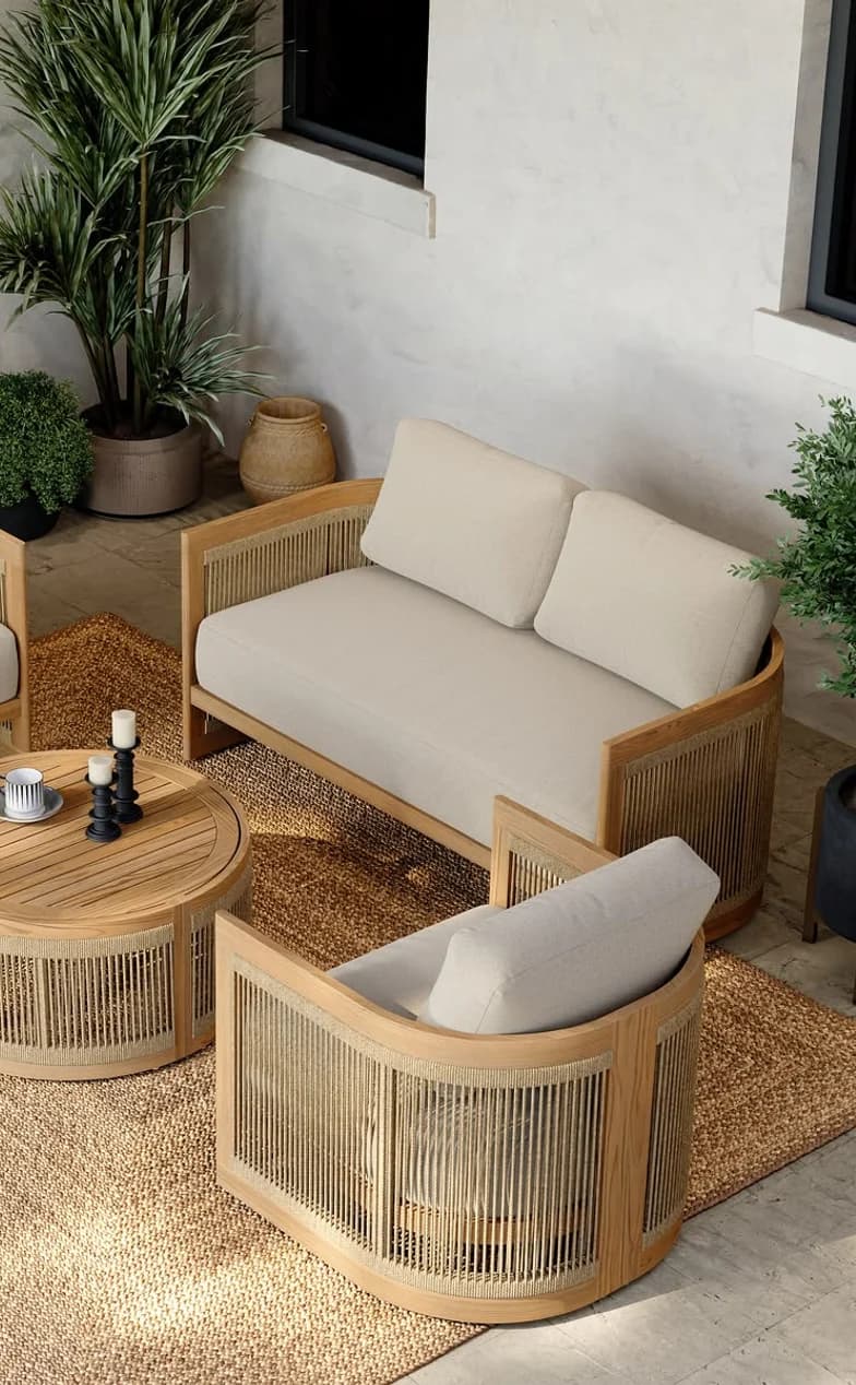 A woven outdoor sofa and armchair on a shaded terrace