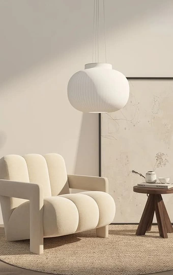 A bouclé armchair beside a paper globe lamp