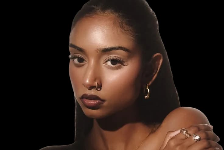 A model wearing a gold septum ring and a hoop earring