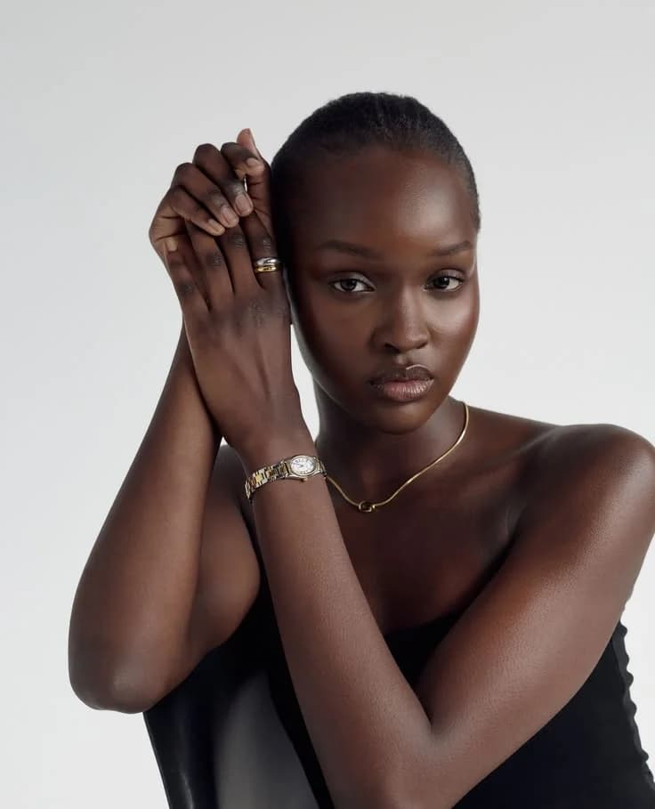 A model resting her chin on a hand wearing a slim watch