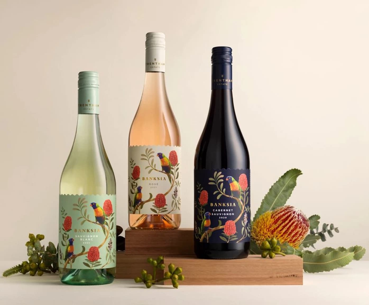 Three illustrated wine bottles on a wooden crate with native flowers