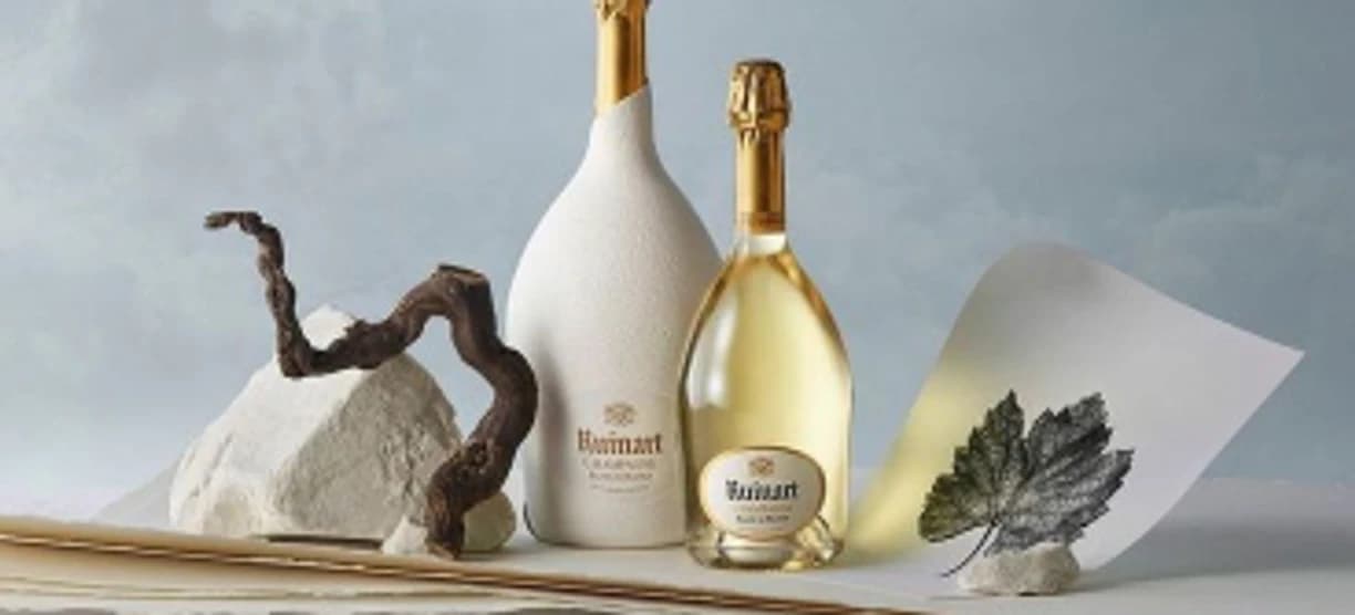 A pale champagne bottle and a gold-capped magnum on slate