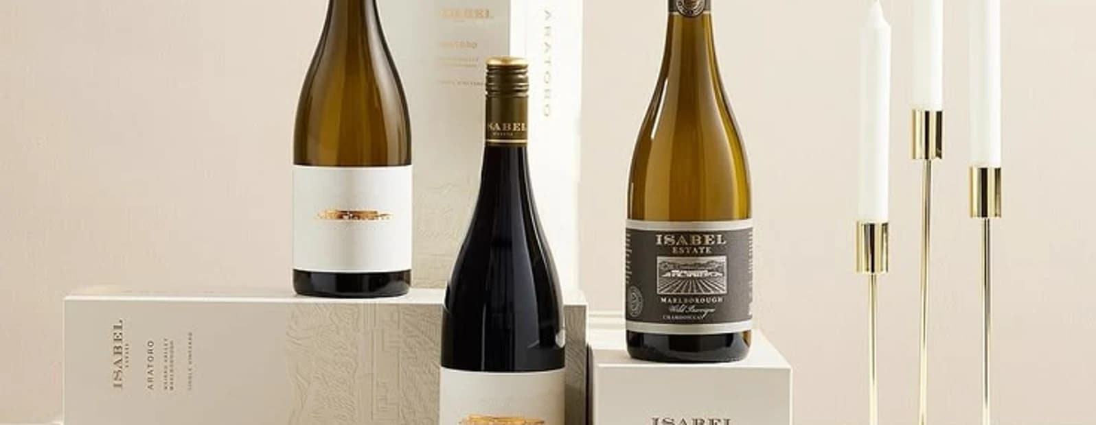 Three wine bottles beside tapered candles and printed cards