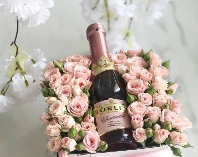 A champagne bottle set into a bouquet of pink roses