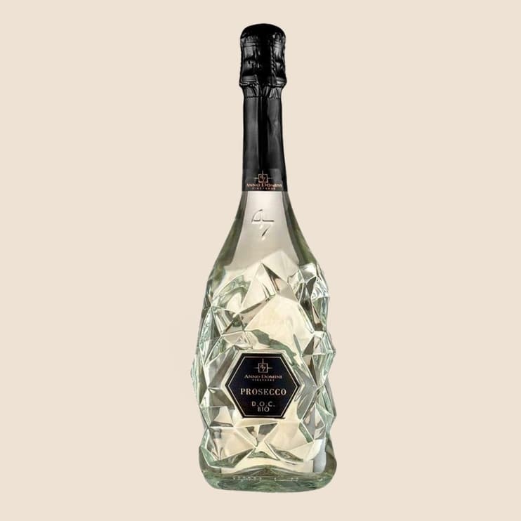 A faceted clear sparkling wine bottle with a black foil
