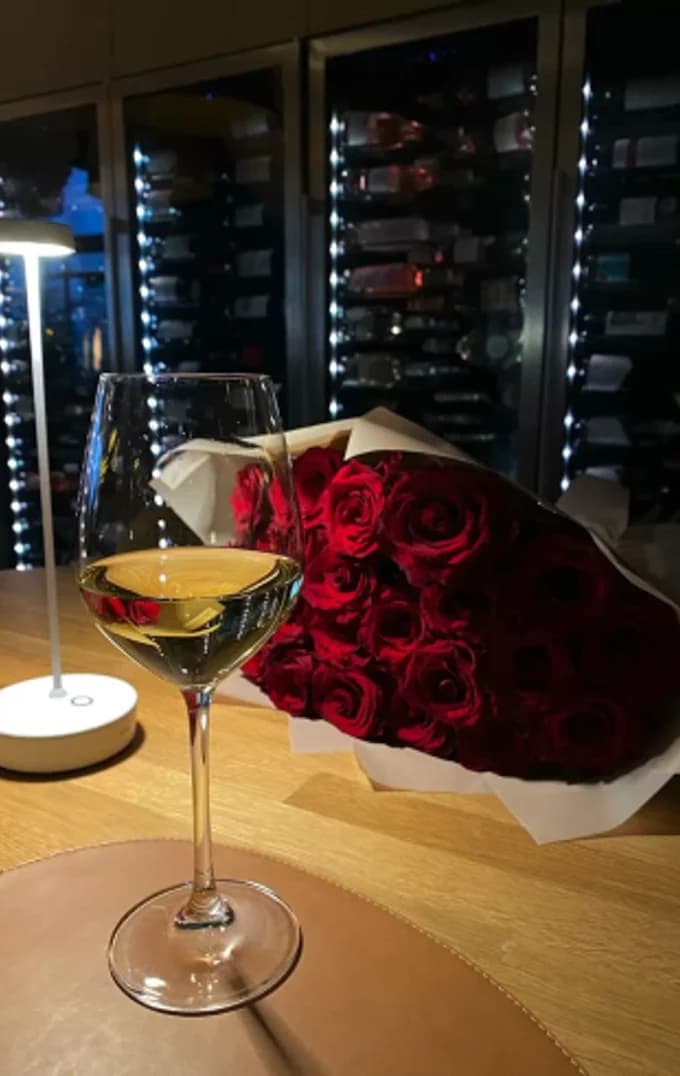 A martini beside a bunch of red roses on a dark table