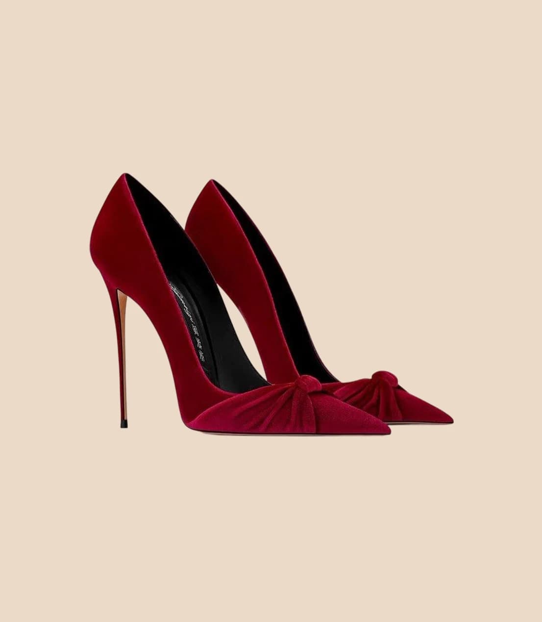 A pair of red velvet stiletto pumps with knotted bows at the toe