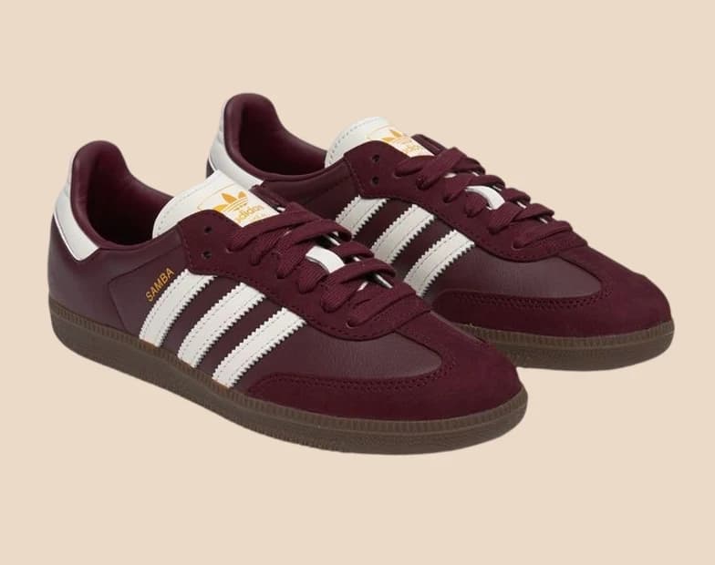 Burgundy suede trainers with white side stripes and a gum sole