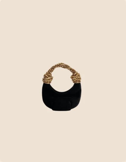 A black velvet crescent bag with a woven gold handle