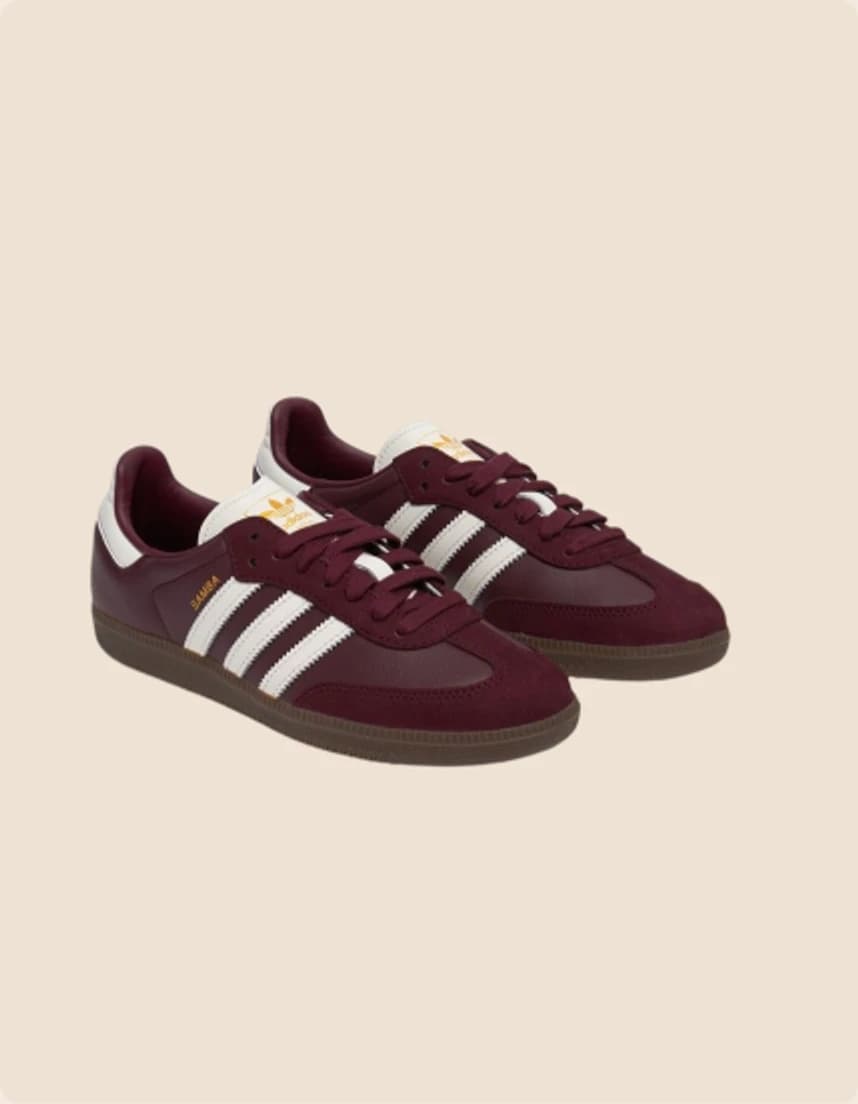 A burgundy suede trainer with three white stripes