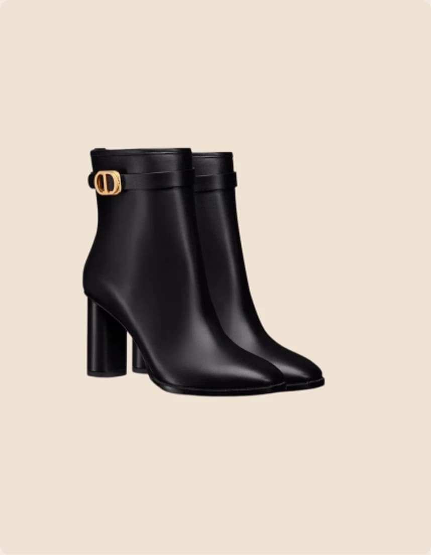 A black leather ankle boot on a block heel with a gold buckle