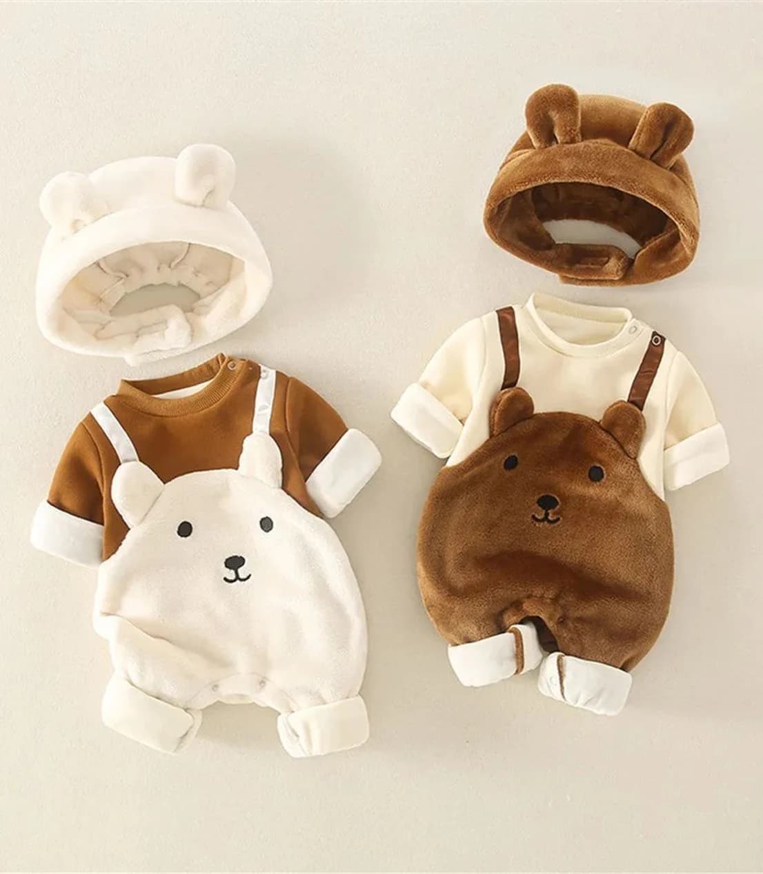 Two bear-eared pramsuits laid flat