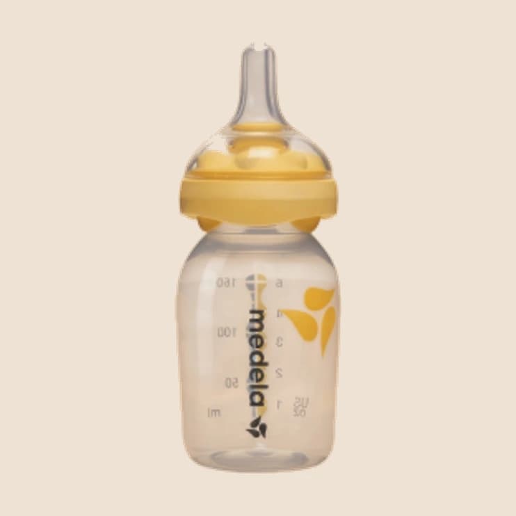 A glass baby bottle with a yellow teat and collar