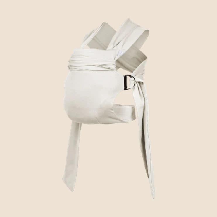 A cream fabric baby carrier wrap with buckled straps