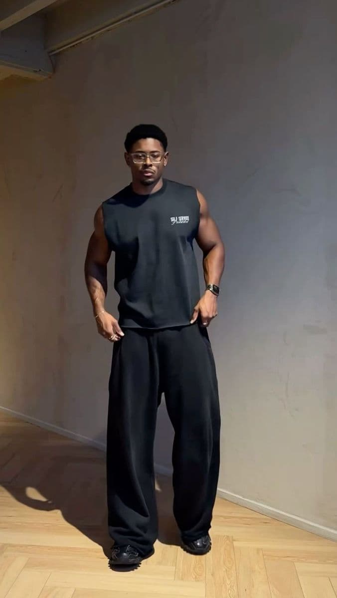 Model in a black sleeveless top and wide trousers