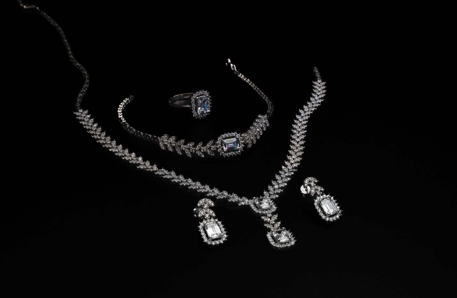 A diamond necklace, bracelet, ring and drop earrings on black