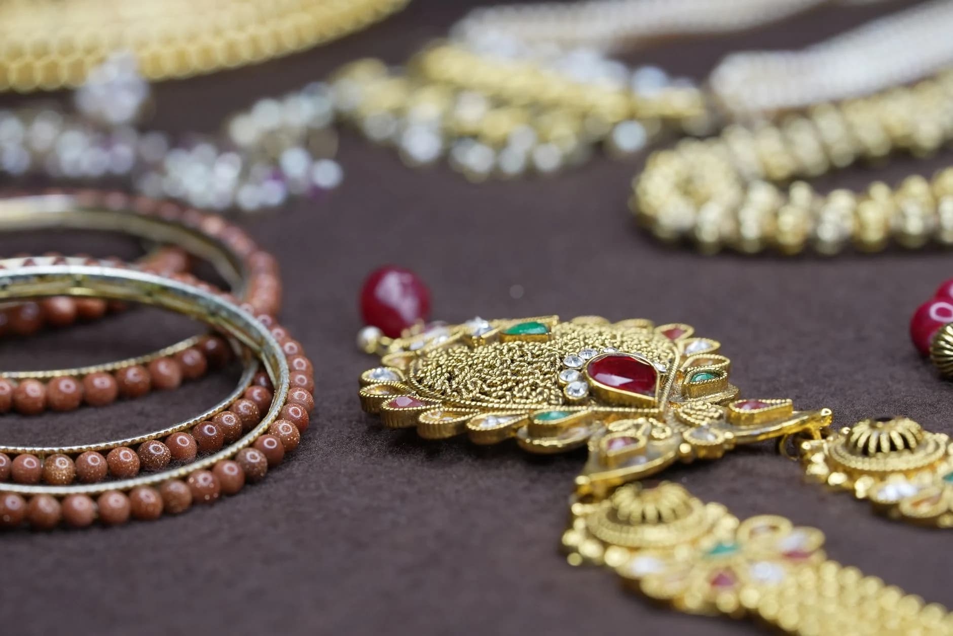 A gold kundan collar and bangles laid on a dark cloth